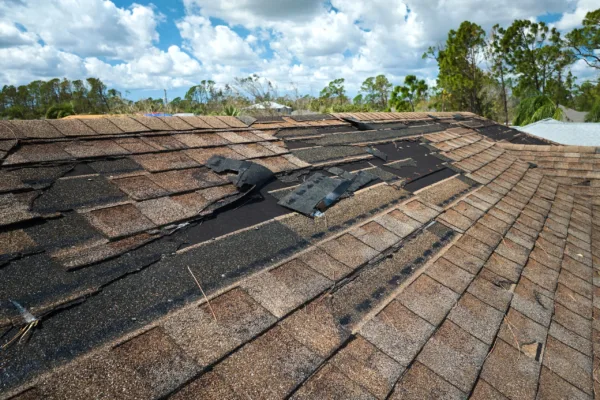 Damaged house roof with missing shingles after hurricane Ian in Florida. Consequences of natural disaster